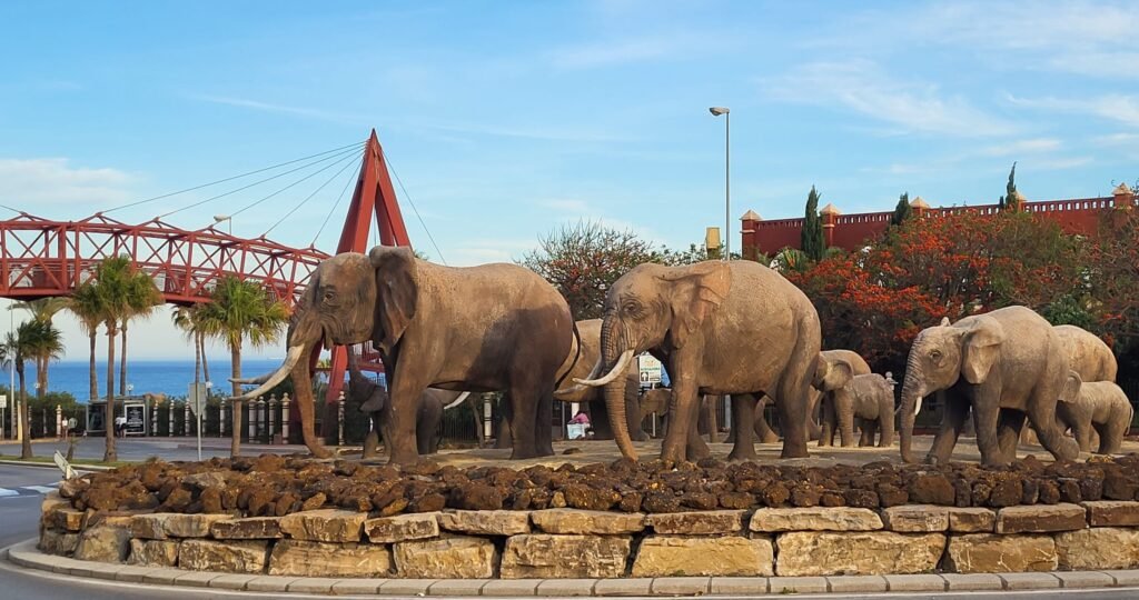 A sculptural group of life-size elephants marching across a roundabout